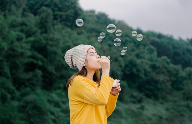 Foto donna asiatica che soffia bolle nel parco.