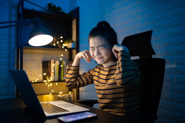 Asian woman bored and annoyed covering her ears  working overtime at home. . Work from home for avoid the Coronavirus COVID 19 concept.