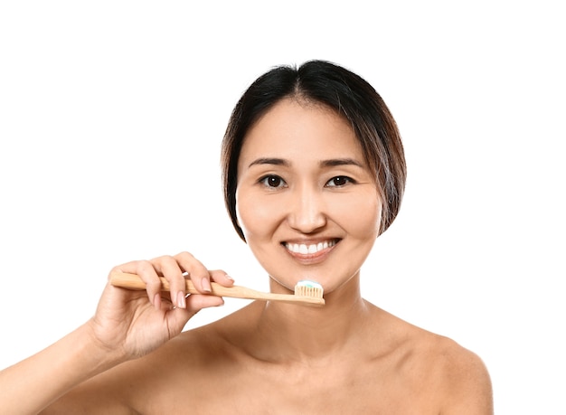 Asian woman brushing teeth on white