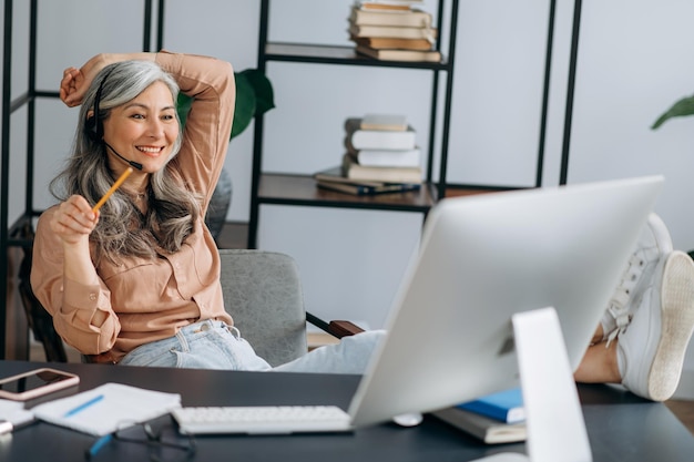 Asian woman business leader conference call throws feet on\
table smiling