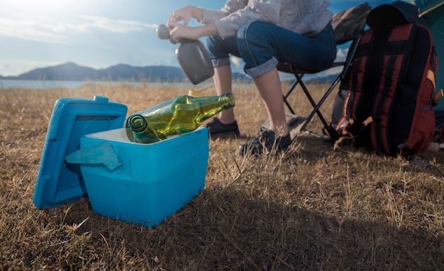 アジア人女性キャンプとバックパック旅行 座って飲み物と一緒に一人でリラックス ビール水を爽やかに