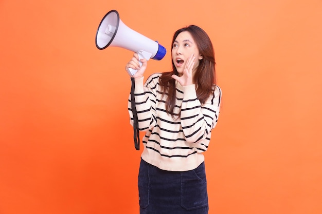 Asian woman candid screaming expression standing holding megaphone loudspeaker for warning while han