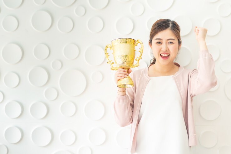 Photo アジアの女性は黄金のトロフィーで成功を祝う