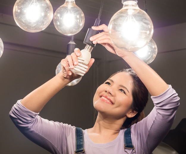 Asian woman changing light bulb