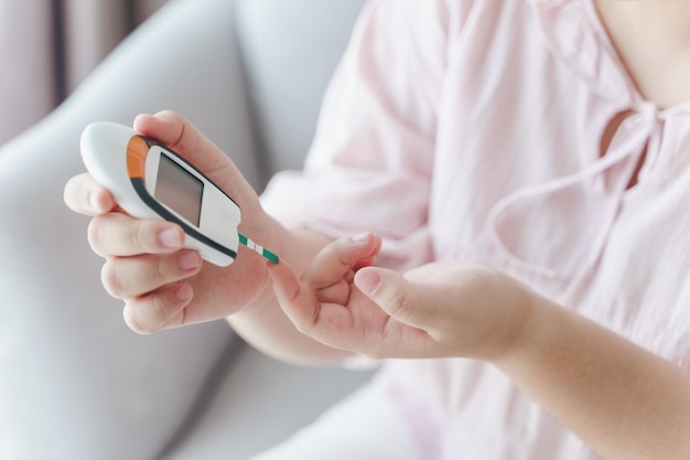 Donna asiatica che controlla il livello di zucchero nel sangue con il misuratore di glucosio digitale healthcare and medical