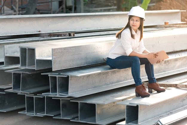 Asian woman civil engineer with white safety helmet visit construction site.