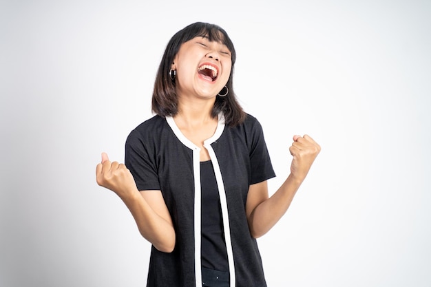 Asian woman clenching hands while celebrating success