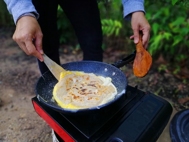 사진 야외 캠핑 중 숲에서 로티 카나이를 요리하는 아시아 여성