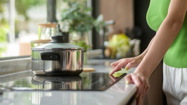 Asian woman cooking and smelling tasting soup in a pot in the kitchen table at home