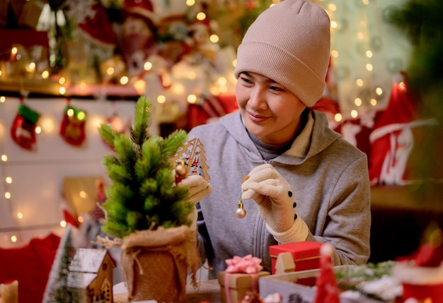 La donna asiatica decora per natale da sola a casa. la famiglia festeggia e felice anno nuovo a casa.