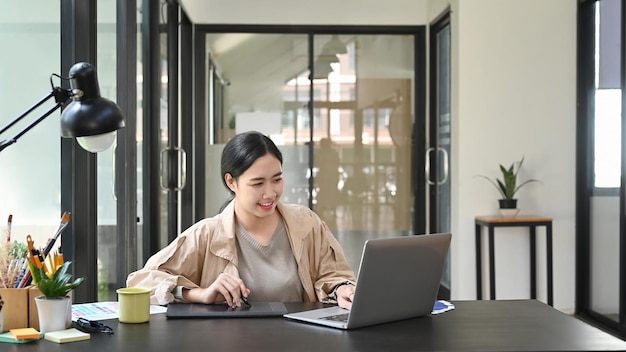 Asian woman designer working with laptop in creative office.