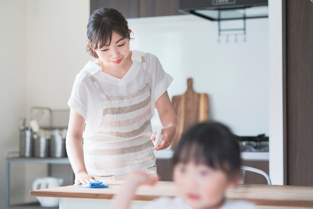 Asian woman disinfecting home dining table with spray