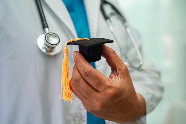 Asian woman doctor holding graduation hat in hospital Medical education concept