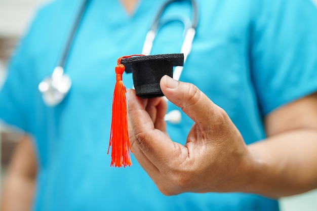 Asian woman doctor holding graduation hat in hospital medical\
education concept