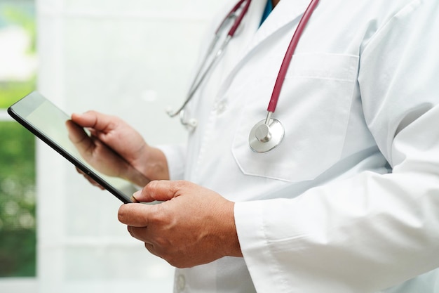 Asian woman doctor holding mobile phone or tablet for search method of treatment patient in hospital