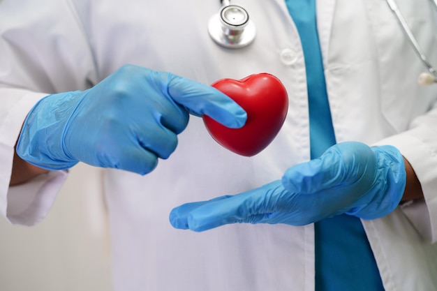 Asian woman doctor holding red heart for health in hospital