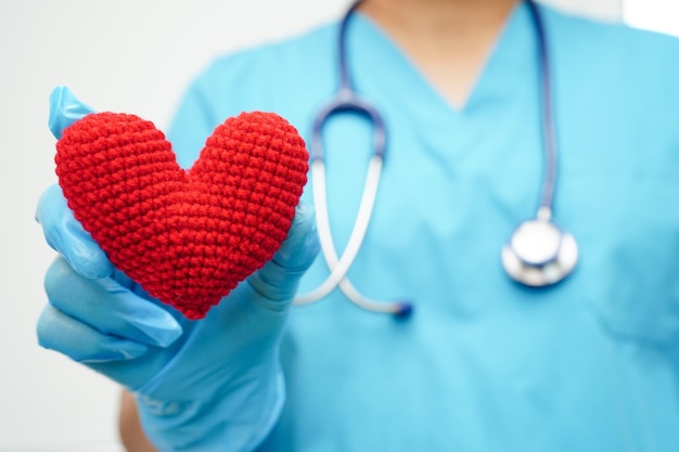 Asian woman doctor holding red heart for health in hospital