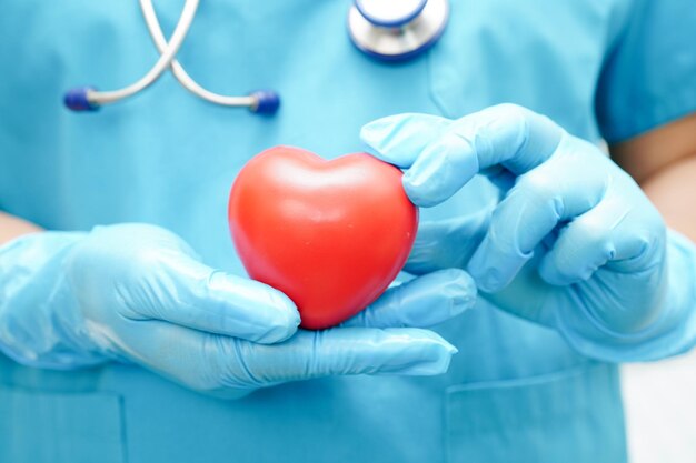 Photo asian woman doctor holding red heart for health in hospital