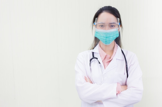 Asian woman doctor in white lab coat wears medical face mask and face shield to protect Coronavirus