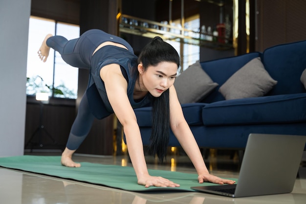 Asian woman does physical exercise training online at home