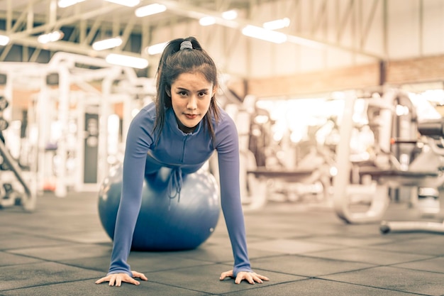 Foto donna asiatica che fa esercizio sulla palla fitness in palestra