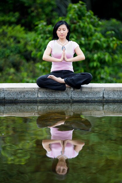 Photo asian woman doing yoga by the lake