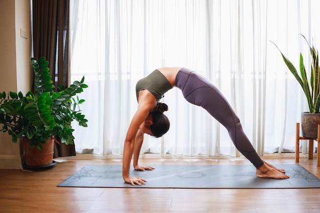 Asian woman doing yoga at home New normal lifestyle concept Healthy lifestyle Relaxing at home