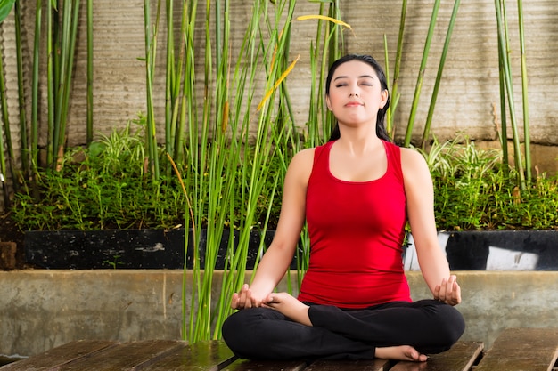 Asian woman doing yoga in tropical setting