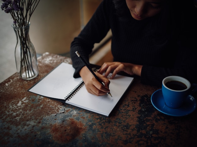 Photo asian woman drawing on paper in coffee shop cafe