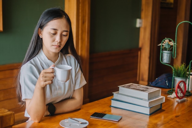 Asian woman drinking coffee in cafe and using telephone for working business online marketing