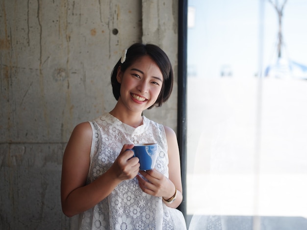 アジアの女性がカフェでコーヒーを飲む