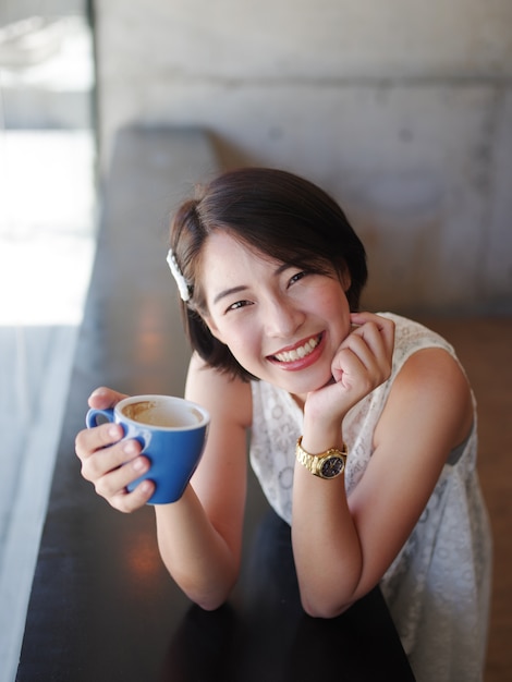 Donna asiatica che beve caffè nella caffetteria