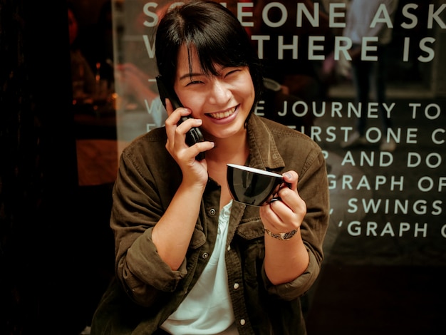 アジアの女性がカフェでコーヒーを飲む