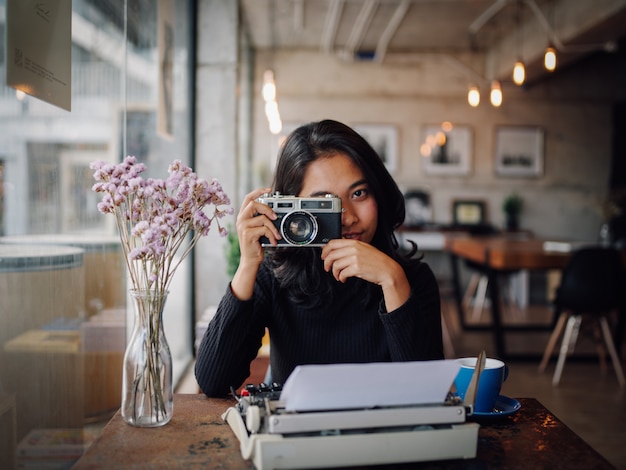 Азиатская женщина, пить кофе в кафе кафе с старинной камерой