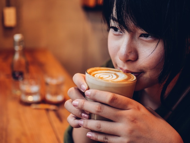 アジアの女性がコーヒーショップカフェでコーヒーを飲む