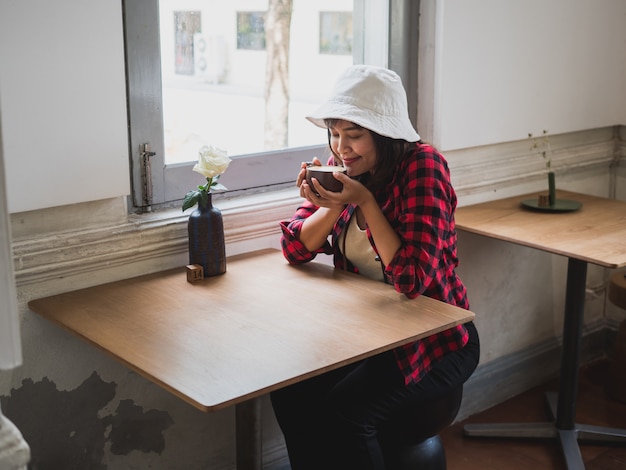 アジアの女性がコーヒーショップカフェでコーヒーを飲む