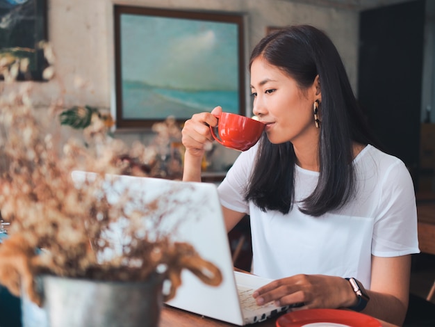 アジアの女性のコーヒーショップカフェでコーヒーを飲む