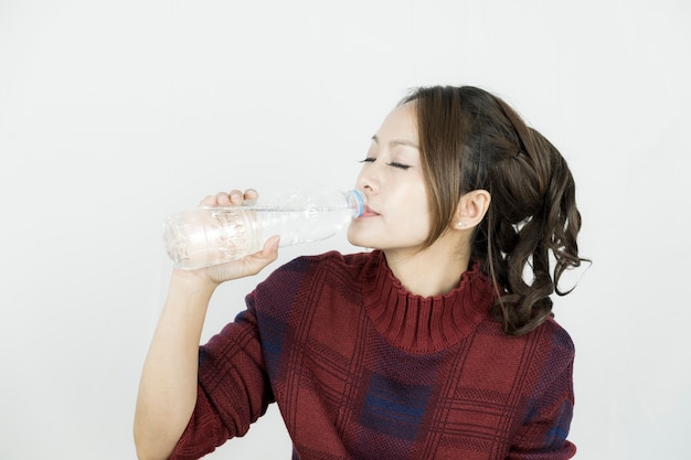 プラスチック製のボトルからアジアの女性の飲み水。