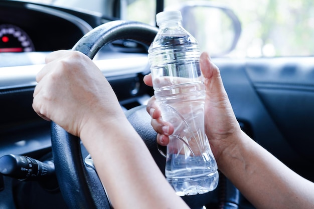 Asian woman driver hold cold water for drink in car dangerous and risk an accident