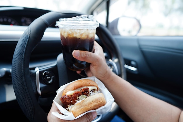 Asian woman driver hold and eat hamburger in car dangerous and risk an accident