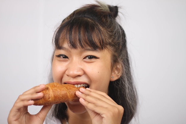 흰색 배경에 고립 된 빵을 먹는 아시아 여자