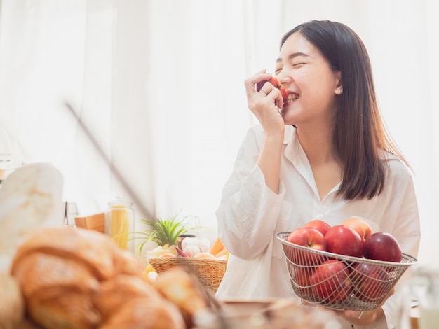 Photo asian woman eating fruit in the kitchen