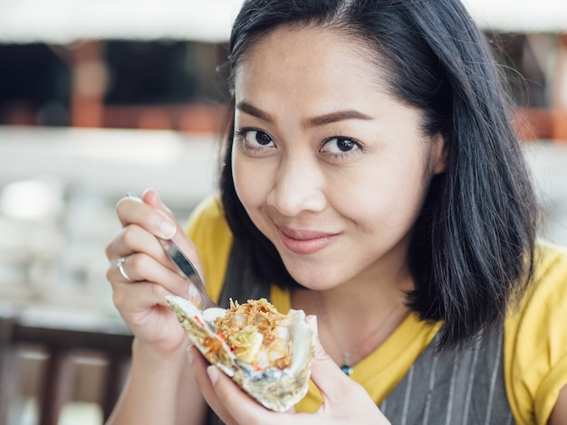 Asian woman eats Thai style fresh oyster with garlic