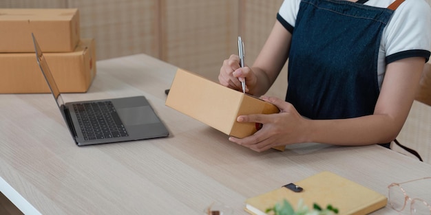 Asian woman an ecommerce business is writing a list of customers on paper before shipping to them she runs an ecommerce business on websites and social media Concept of selling products online