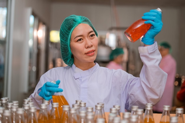 Asian woman employee working Food quality control in Factory and worker inspecting production line beverage tanker in of dairy factory Concept food industry