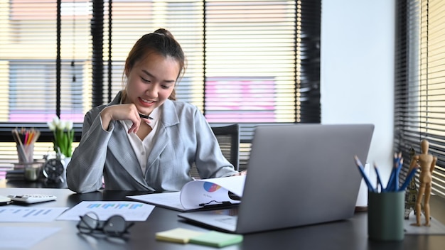 Asian woman entrepreneur working with financial document in modern office