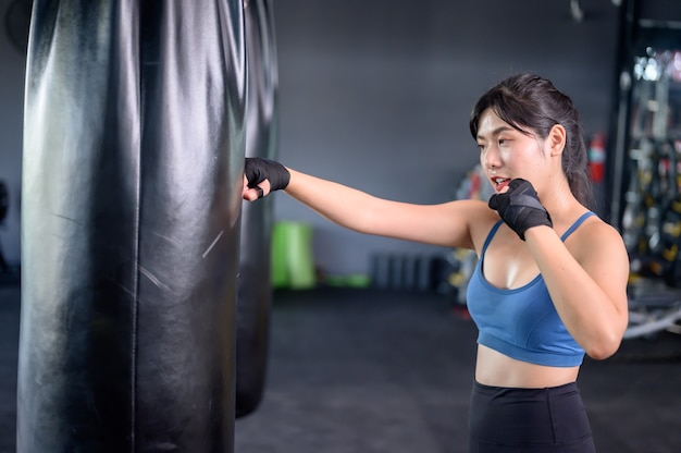 Asian woman exercise and lifestyle at fitness gym. Sporty woman workout and boxing with trainer. Wellness and healthy for bodybuilding.