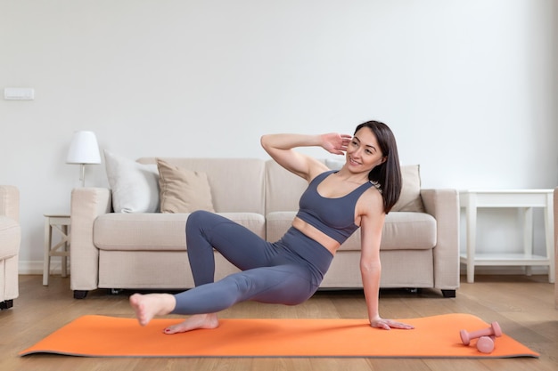 Asian woman exercising at home stretching Time for yoga Attractive and healthy young woman doing exercises while resting at home Young woman exercising at home interior