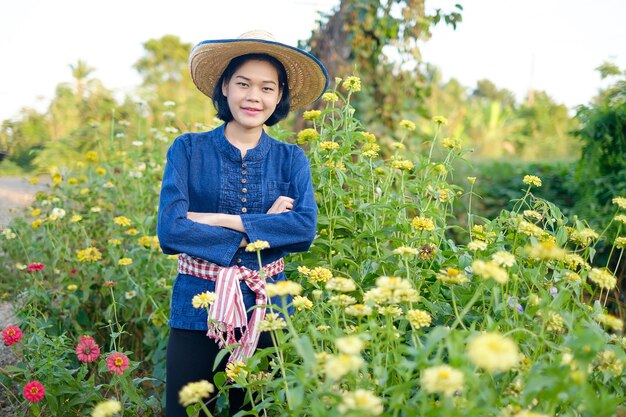 花畑に立っているアジアの女性農家の腕を組んで