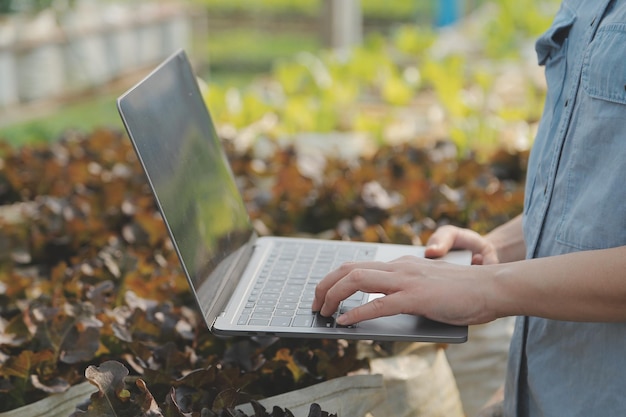 Asian woman farmer using digital tablet in vegetable garden at greenhouse Business agriculture technology concept quality smart farmer